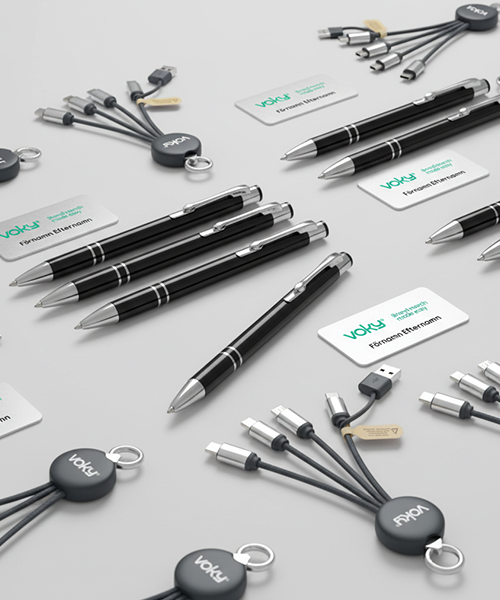 En &ouml;versikt av Voky-m&auml;rkta profilprodukter som inkluderar flera svarta pennor, vita namnskyltar och cirkul&auml;ra multiladdningskablar.