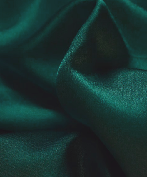 Mörkgrönt tyg i siden reflekterar ljus